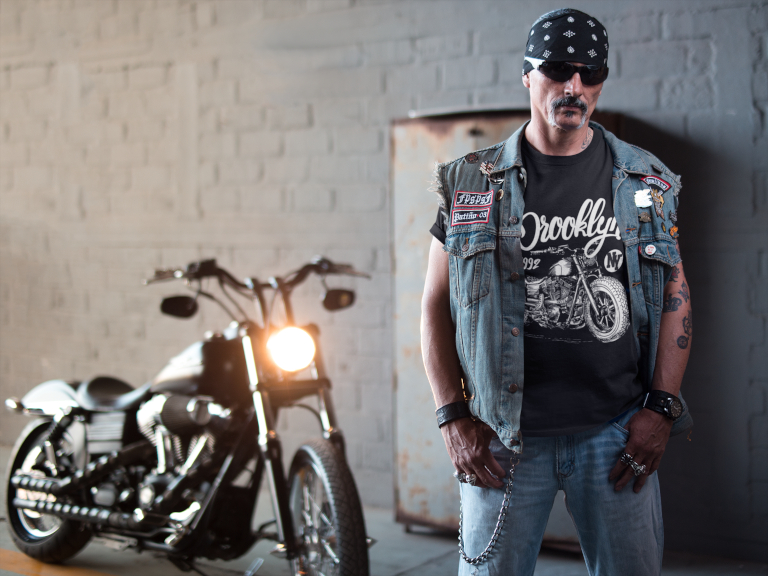 a tattooed biker man wearing a Brand X Alternative Apparel t shirt bandana and chain in front of a motorcycle